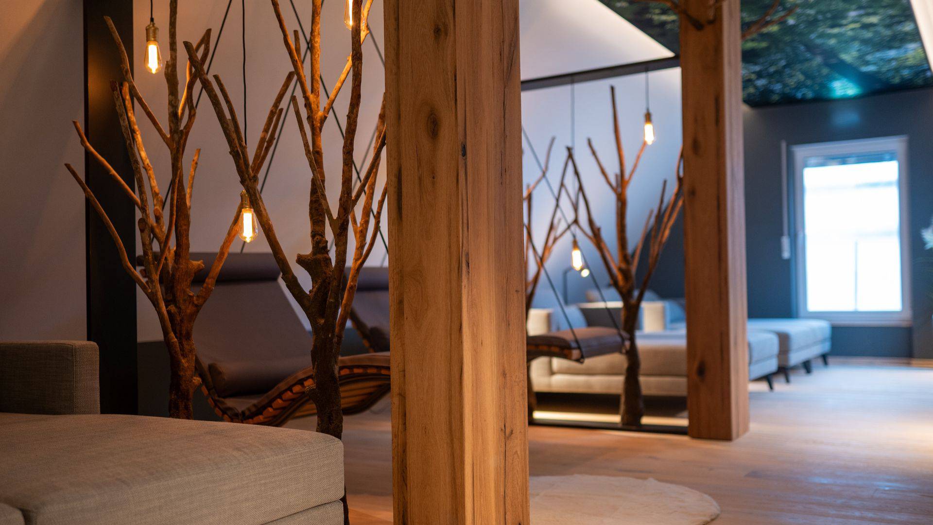 Ruheraum mit Holzsäulen, Liegen und leuchtenden Astlampen im Hotel Leinsweiler Hof in der Pfalz