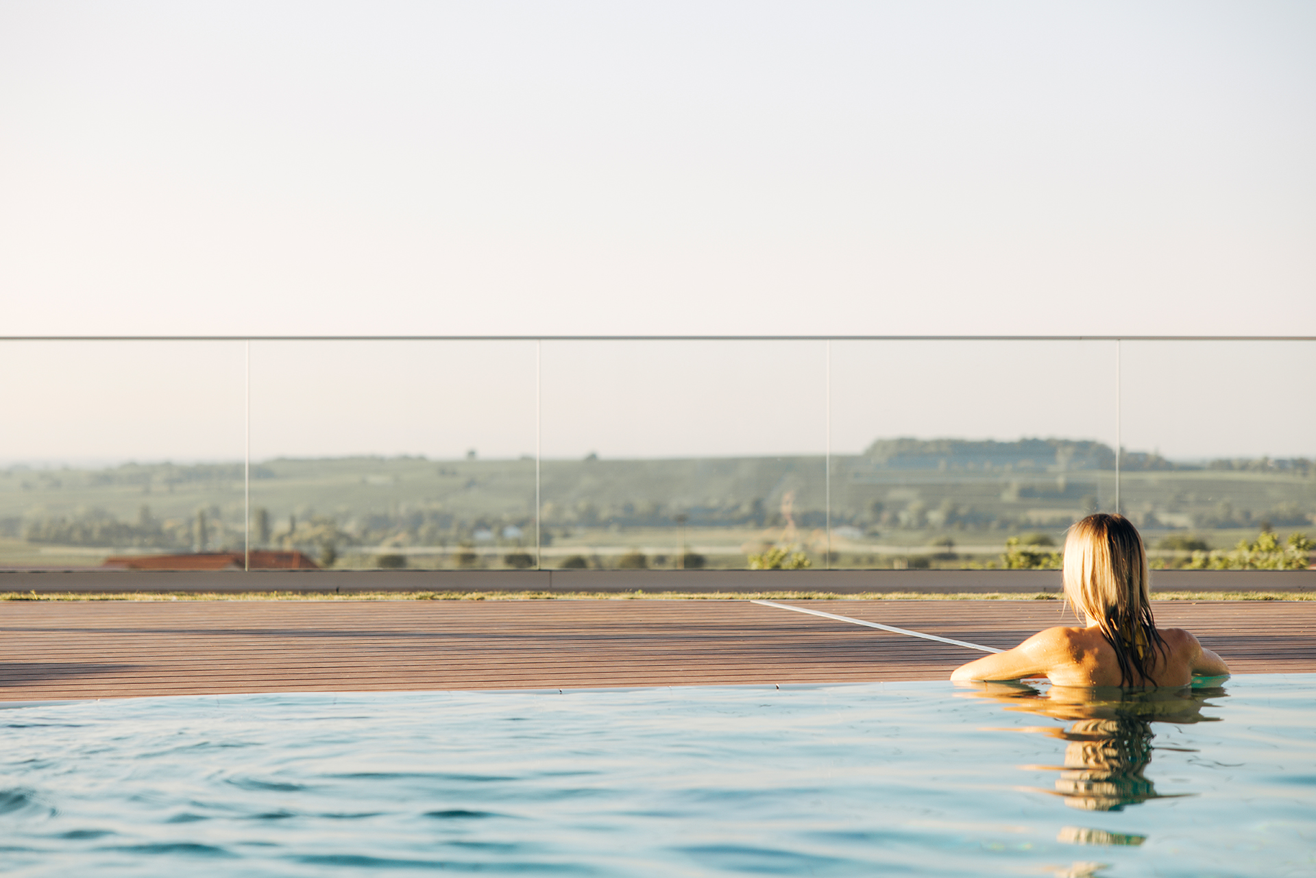 Frau im Außenpool mit Blick über die Weinberge beim Wellnesshotel in der Pfalz